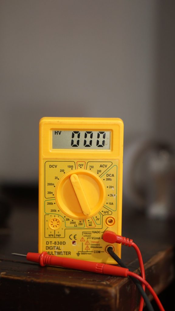 Close-up of a yellow digital multimeter used to test refrigerator electrics