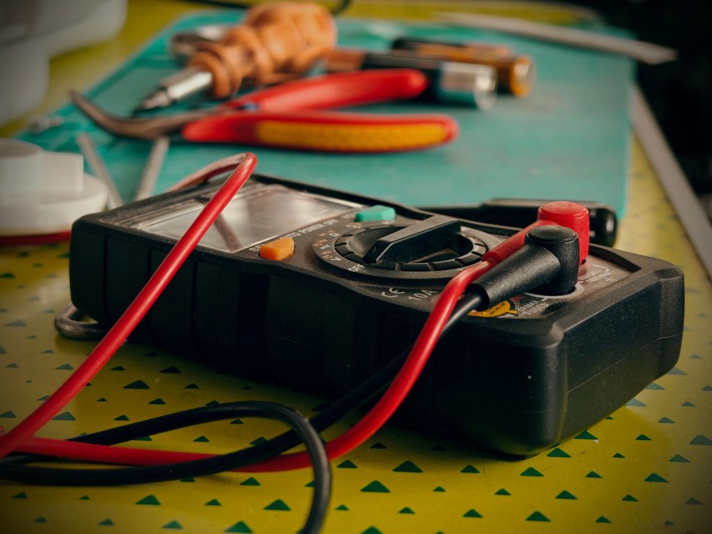Multimeter and repair tools laid out on a technician's workbench