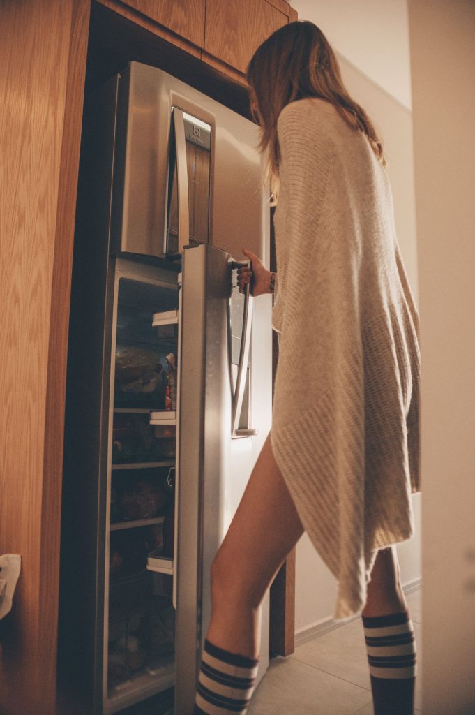 Person opening a refrigerator door in a warmly lit kitchen