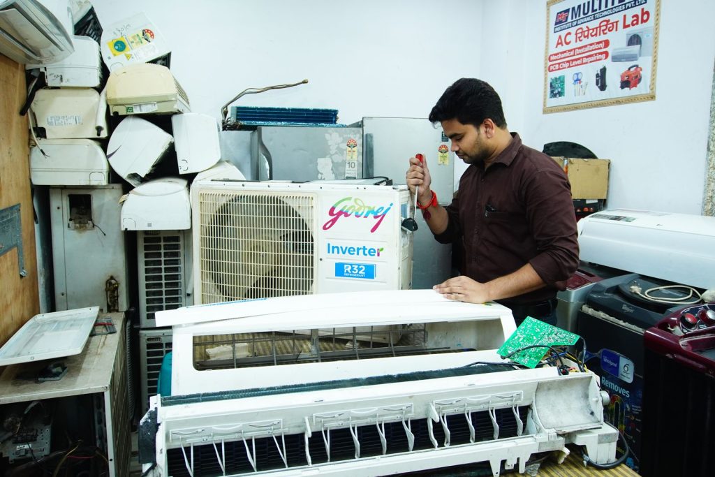 Refrigeration technician working on a cooling unit in a service workshop