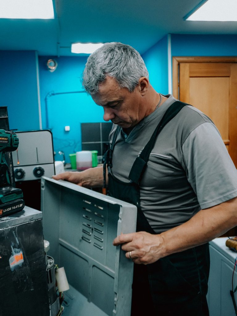 Technician examining the inside of an appliance during a home visit