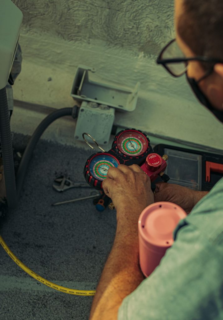 Technician reading a refrigerant manifold gauge during a gas charge