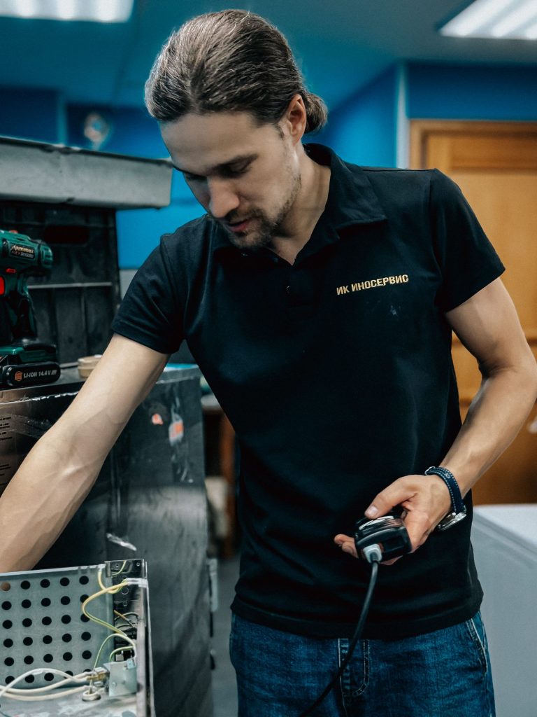 Technician repairing a refrigerator component in a workshop