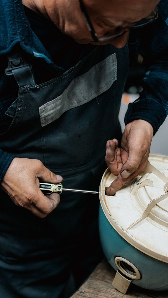 Technician's hands working on appliance tubing with a tool