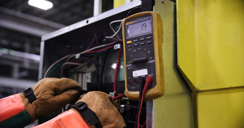 Technician testing refrigerator wiring with a digital multimeter