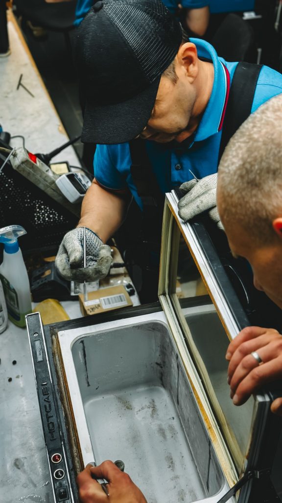 Two technicians repairing an industrial freezer unit
