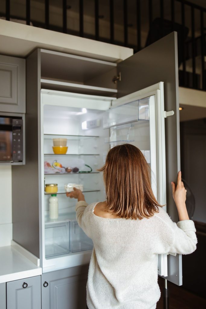 Woman opening a double-door refrigerator in a modern kitchen